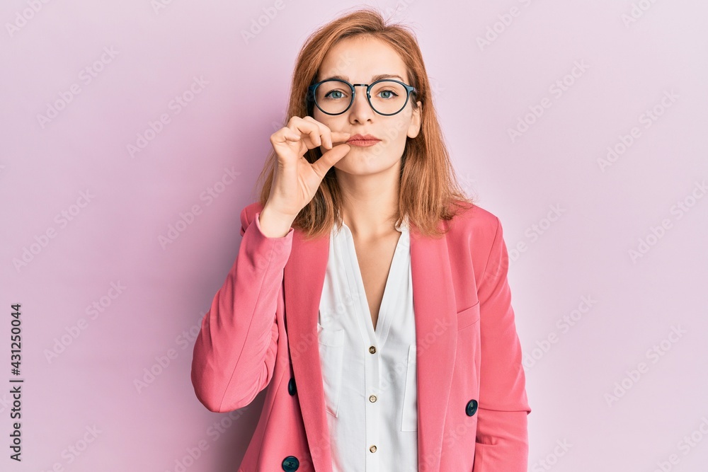 Young caucasian woman wearing business style and glasses mouth and lips shut as zip with fingers. secret and silent, taboo talking
