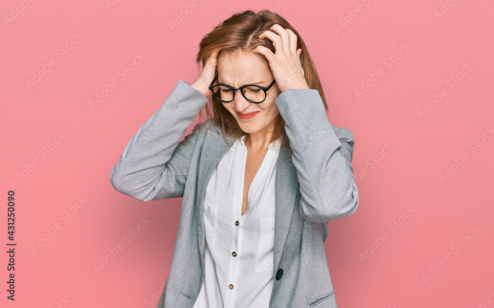 Young caucasian woman wearing business style and glasses suffering from headache desperate and stressed because pain and migraine. hands on head. Young caucasian woman wearing business style and glasses suffering from headache desperate and stressed because pain and migraine. hands on head.