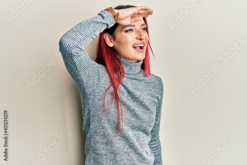 Young caucasian woman wearing casual clothes very happy and smiling looking far away with hand over head. searching concept.