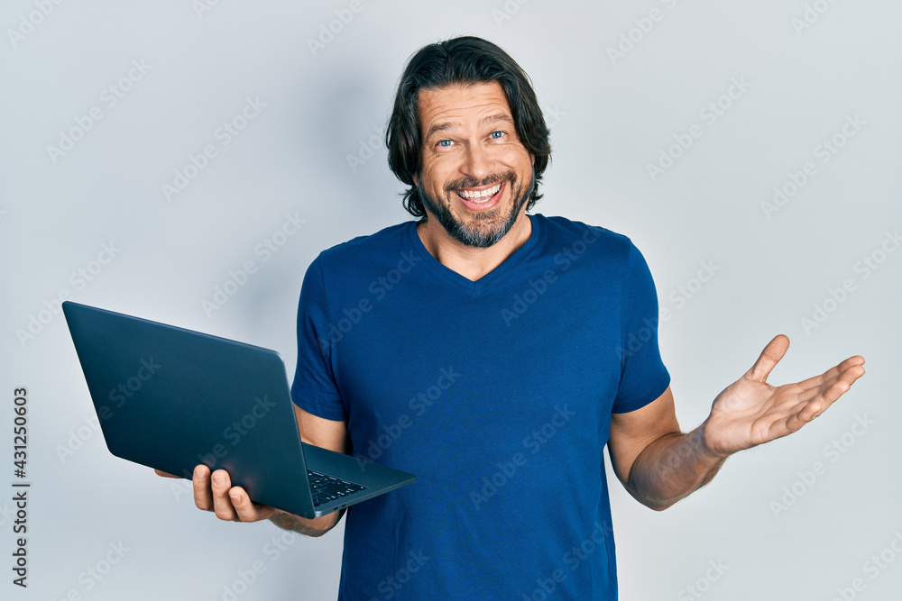 Middle age caucasian man working using computer laptop celebrating achievement with happy smile and winner expression with raised hand Middle age caucasian man working using computer laptop celebrating achievement with happy smile and winner expression with raised hand