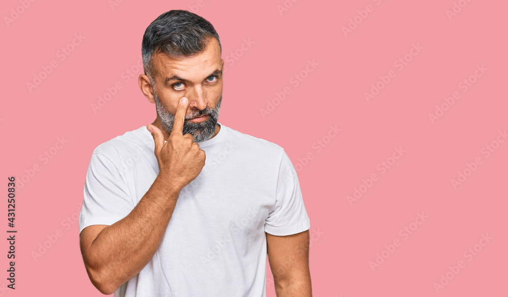 Middle age handsome man wearing casual white tshirt pointing to the eye watching you gesture, suspicious expression