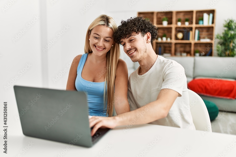 Young couple smiling happy using laptop at home. Young couple smiling happy using laptop at home.