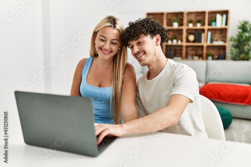 Young couple smiling happy using laptop at home.