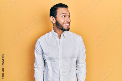 Hispanic man with beard wearing business shirt smiling looking to the side and staring away thinking.