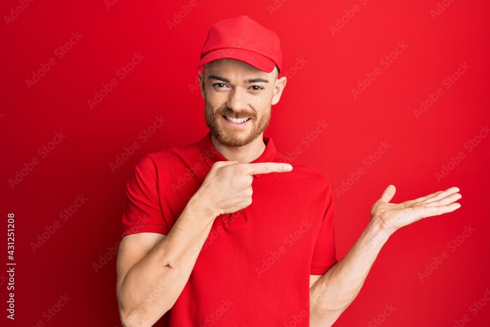 Young redhead man wearing delivery uniform and cap amazed and smiling to the camera while presenting with hand and pointing with finger. Young redhead man wearing delivery uniform and cap amazed and smiling to the camera while presenting with hand and pointing with finger.
