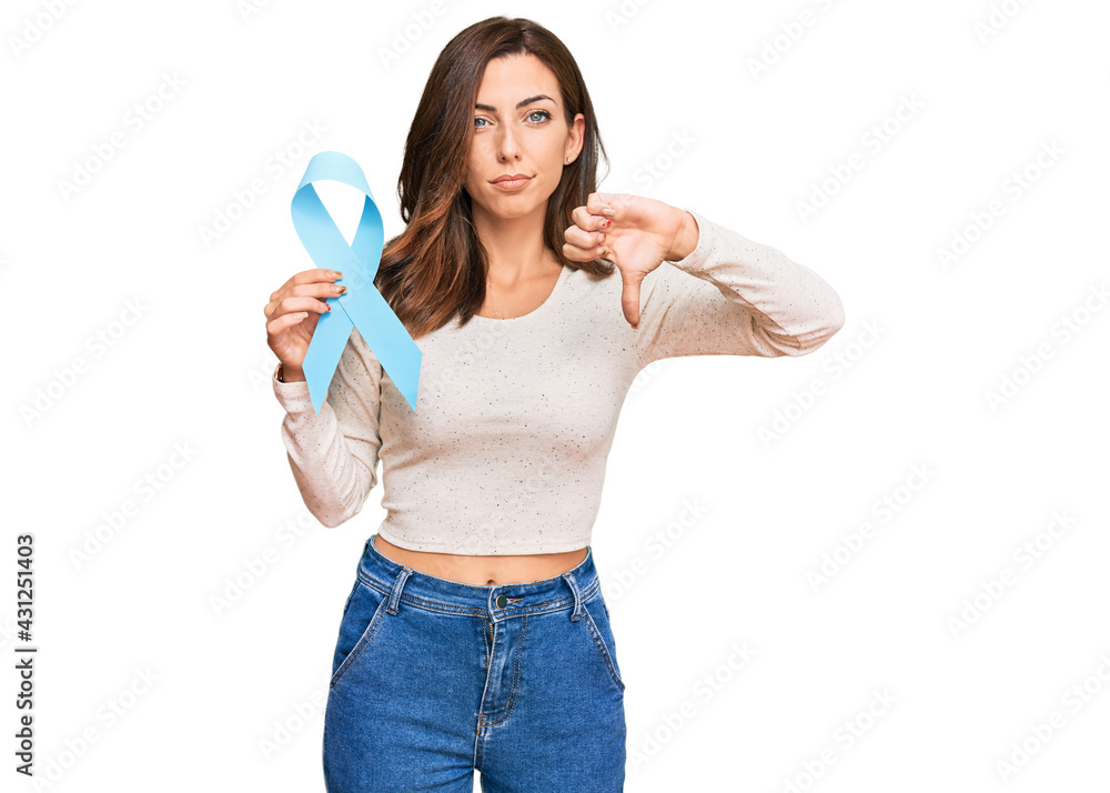 Young brunette woman holding blue ribbon with angry face, negative sign showing dislike with thumbs down, rejection concept Young brunette woman holding blue ribbon with angry face, negative sign showing dislike with thumbs down, rejection concept