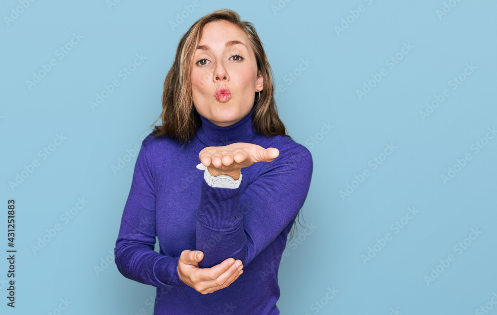 Young blonde woman wearing casual clothes looking at the camera blowing a kiss with hand on air being lovely and sexy. love expression. Young blonde woman wearing casual clothes looking at the camera blowing a kiss with hand on air being lovely and sexy. love expression.