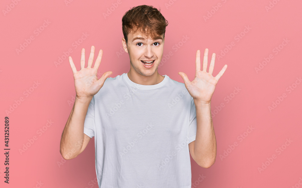 Young caucasian man wearing casual white t shirt showing and pointing up with fingers number ten while smiling confident and happy. Young caucasian man wearing casual white t shirt showing and pointing up with fingers number ten while smiling confident and happy.