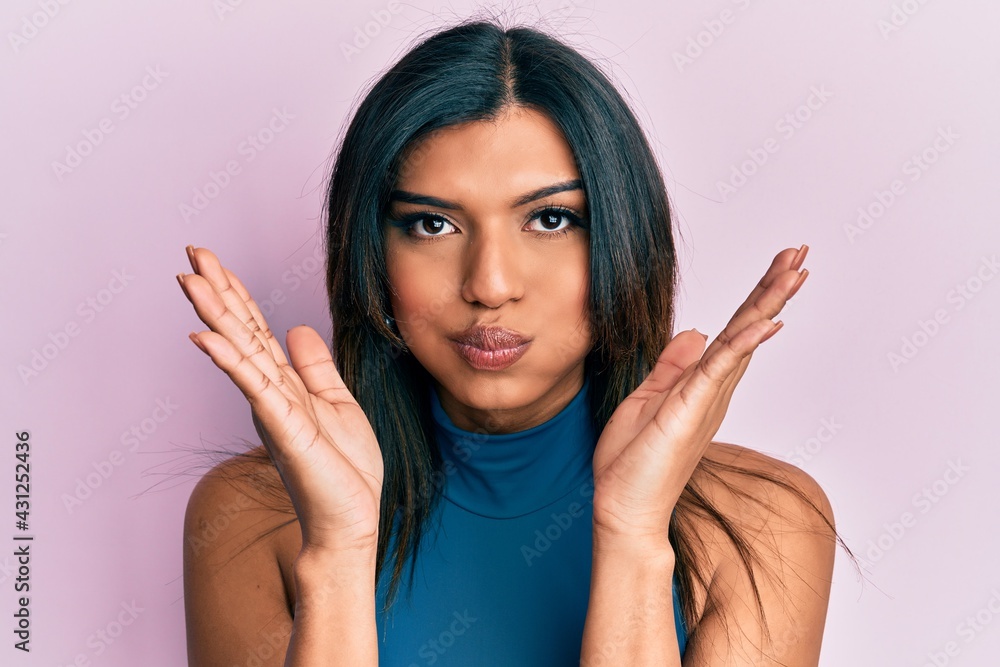 Young latin transsexual transgender woman with hands over face puffing cheeks with funny face. mouth inflated with air, catching air. Young latin transsexual transgender woman with hands over face puffing cheeks with funny face. mouth inflated with air, catching air.
