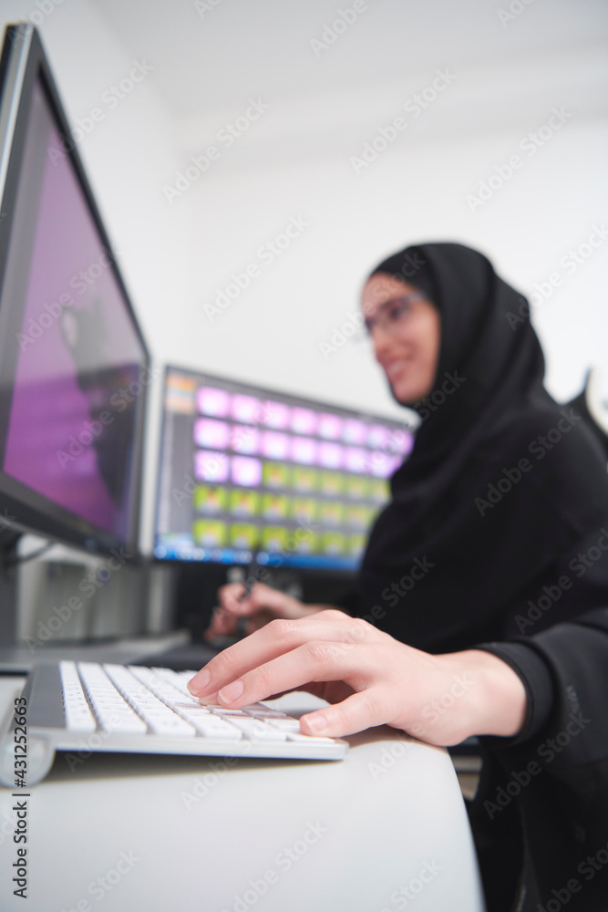 Muslim female graphic designer working on computer using graphic tablet and two monitors Muslim female graphic designer working on computer using graphic tablet and two monitors