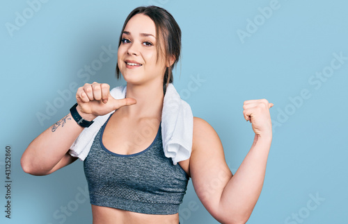 Young hispanic girl wearing sportswear and towel pointing to the back behind with hand and thumbs up, smiling confident © Krakenimages.com