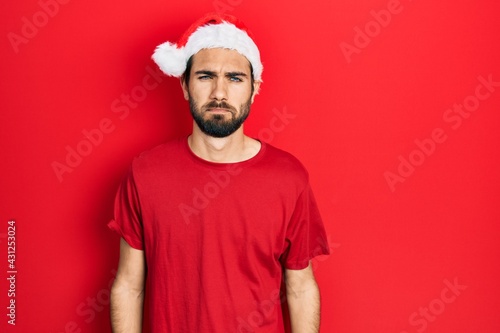 Young hispanic man wearing christmas hat depressed and worry for distress, crying angry and afraid. sad expression.