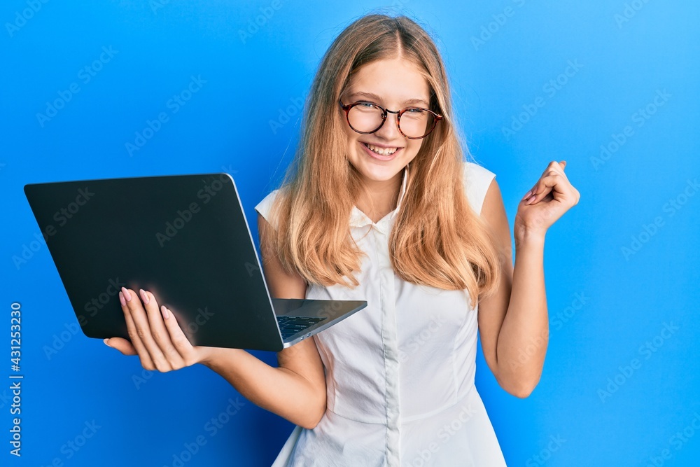 Beautiful young caucasian girl working using computer laptop screaming proud, celebrating victory and success very excited with raised arm Beautiful young caucasian girl working using computer laptop screaming proud, celebrating victory and success very excited with raised arm