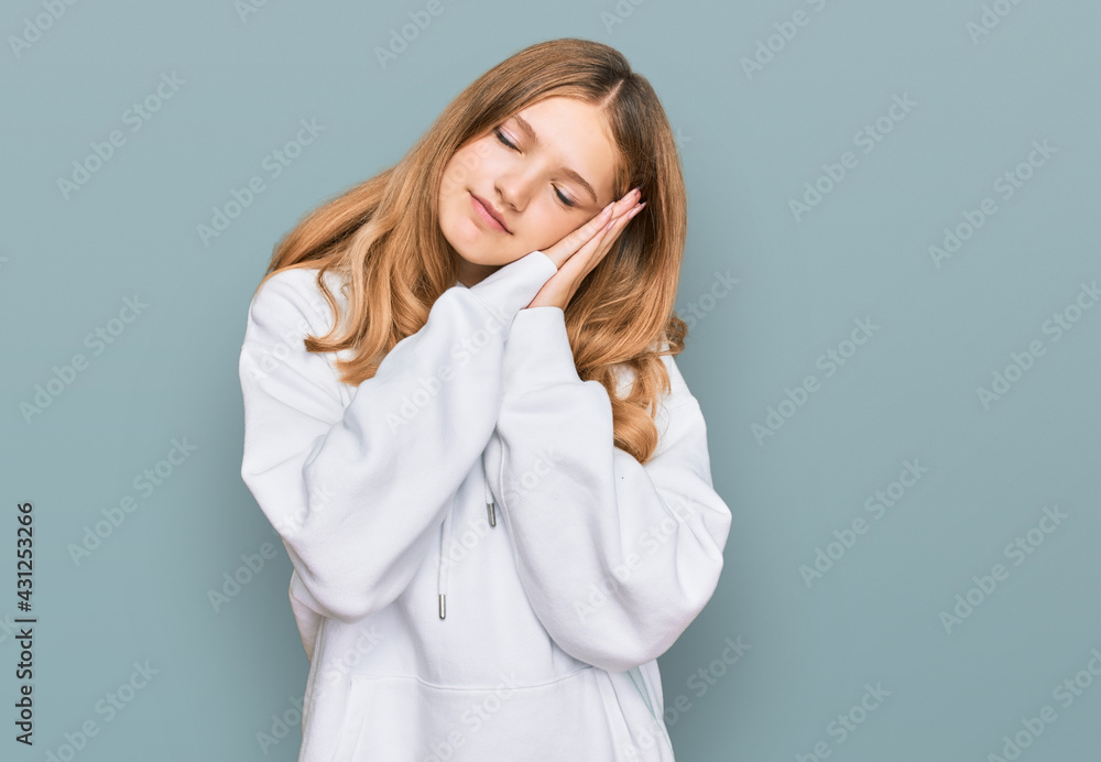 Beautiful young caucasian girl wearing casual sweatshirt sleeping tired dreaming and posing with hands together while smiling with closed eyes. Beautiful young caucasian girl wearing casual sweatshirt sleeping tired dreaming and posing with hands together while smiling with closed eyes.