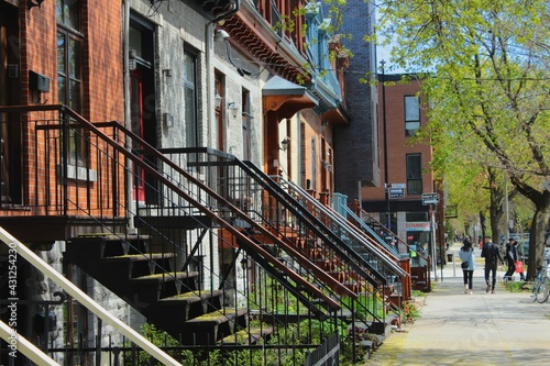 Montreal city street in spring season, in the month of April, with beautiful old houses of different colors on a sunny day. Urban architecture of Canada on Plateau Mont Royal.