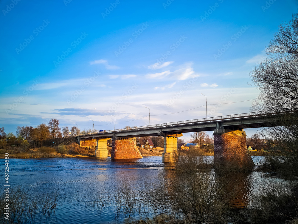 Ancient bridge over the river with stone pillars. Rapid flow of water in spring. Sunset view. Ancient bridge over the river with stone pillars. Rapid flow of water in spring. Sunset view.