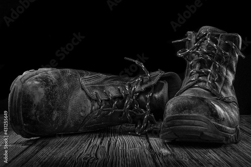 old working electricians boots on a vintage wooden floor, light painting, still lfe black and white photography