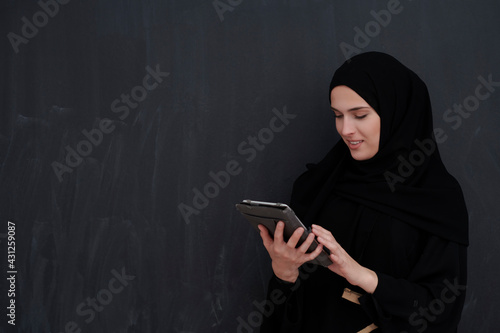 Young Arab businesswoman in traditional clothes or abaya holding tablet computer
