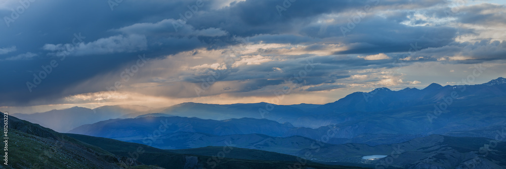 Rainy weather in the mountains, evening light. Panoramic view.