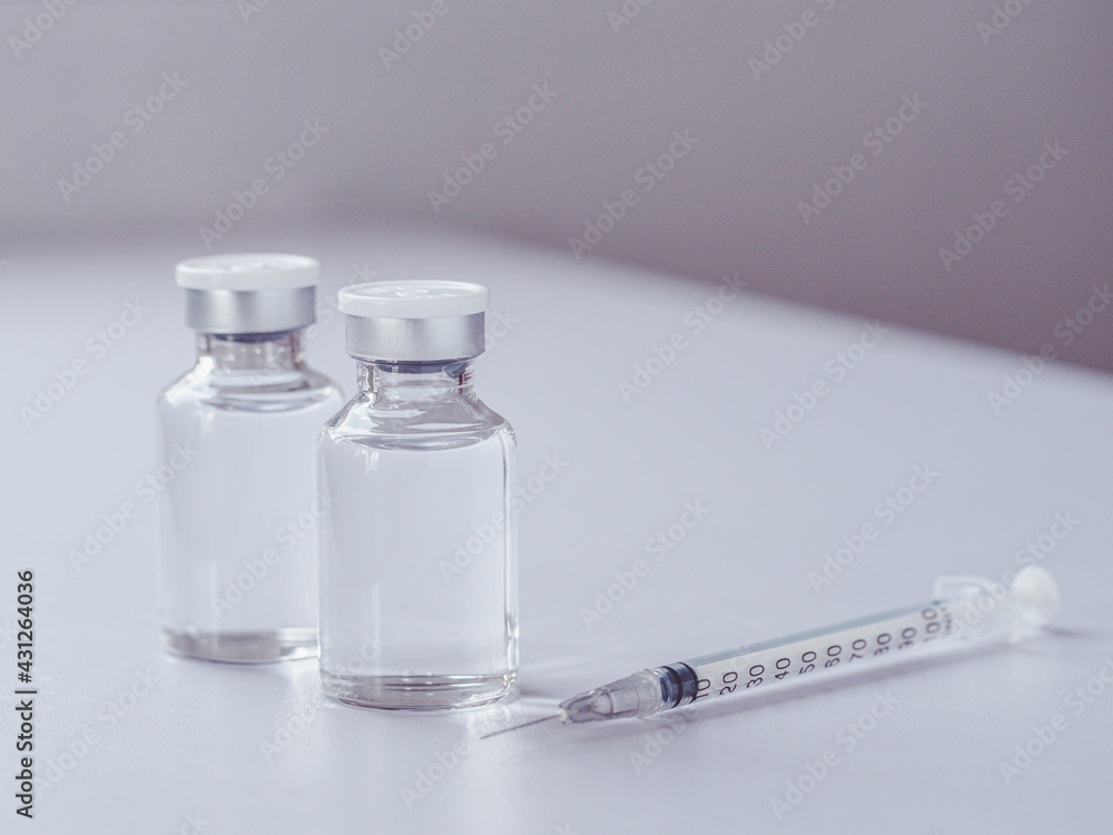 Close up, Two bottles of covid 19 coronavirus vaccine and a syringe on the white table and space for word. The medical conception of combating the covid-19 pandemic. Close up, Two bottles of covid 19 coronavirus vaccine and a syringe on the white table and space for word. The medical conception of combating the covid-19 pandemic.