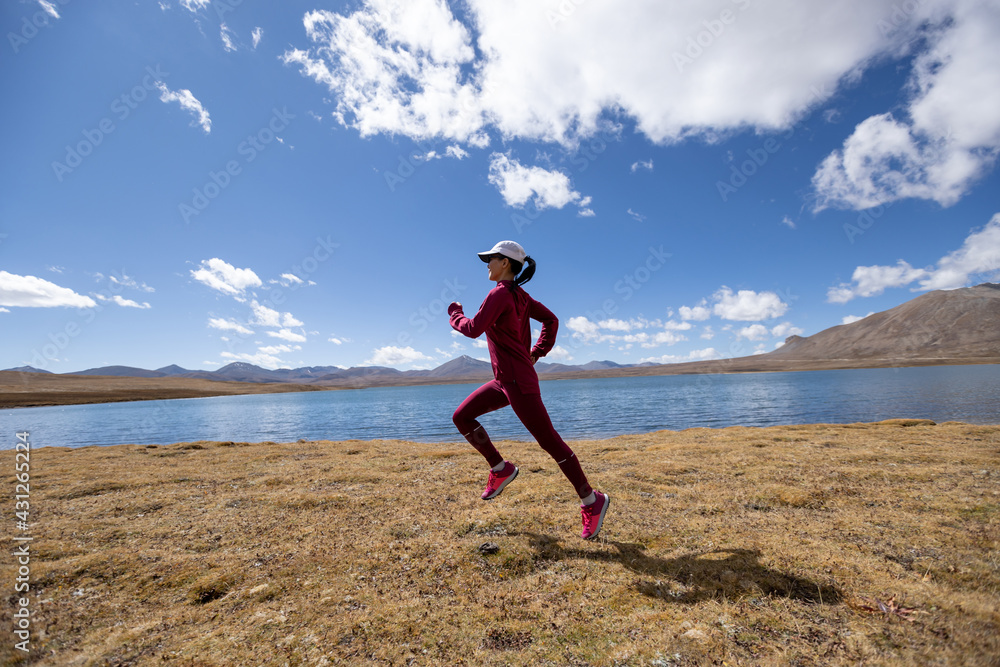 Woman trail runner cross country running on winter lakeside Woman trail runner cross country running on winter lakeside