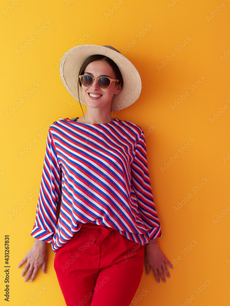 Portrait of young woman wearing sunglasses and hat over a yellow background