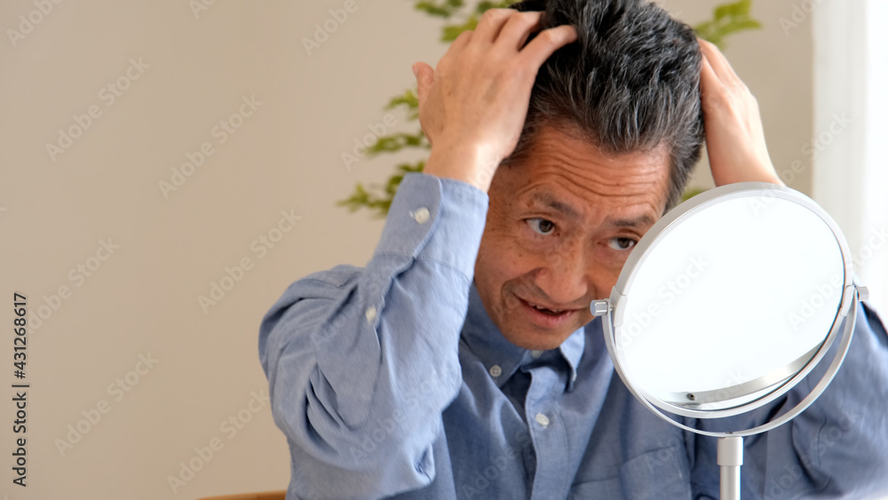 リビングの鏡でヘアセットをするシニア男性