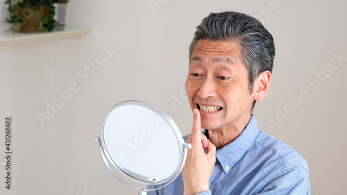 リビングで歯のチェックをするシニア男性