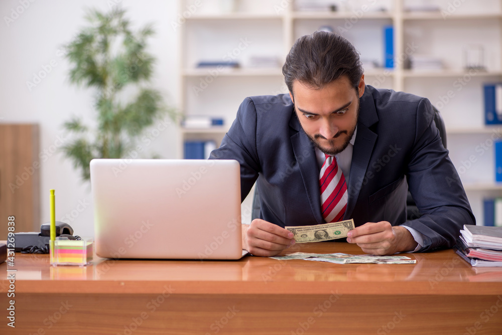 Young male employee holding banknotes in the office Young male employee holding banknotes in the office