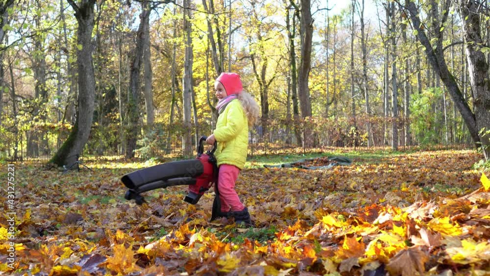 Excited little girl holding leaf blower tool in autumn garden. Child blow leaves Excited little girl holding leaf blower tool in autumn garden. Child blow leaves