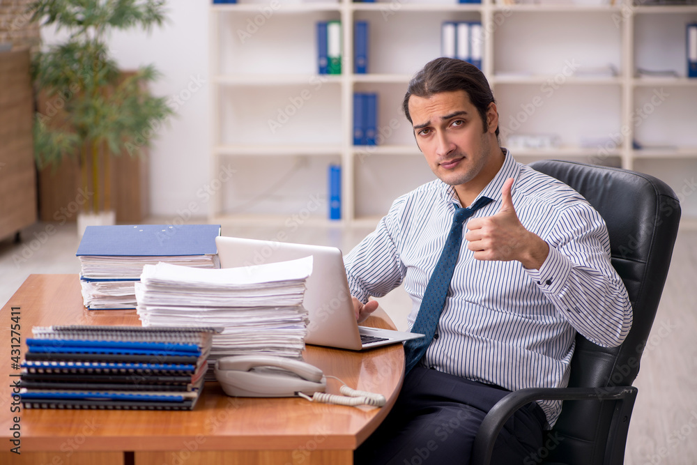 Young male employee unhappy with excessive work in the office Young male employee unhappy with excessive work in the office