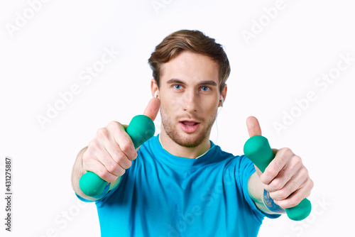 sports man with dumbbells in hands in headphones fitness exercise light background