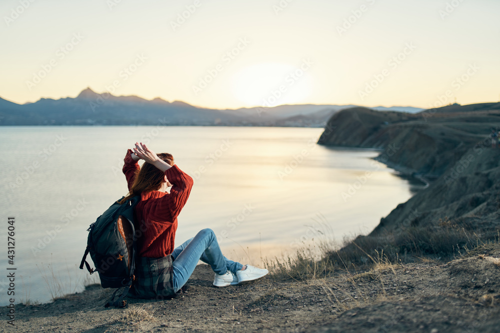 woman tourist with a backpack in the mountains at sunset near the sea top view woman tourist with a backpack in the mountains at sunset near the sea top view
