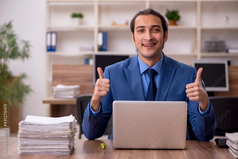 Young male employee and a lot of work in the office Young male employee and a lot of work in the office