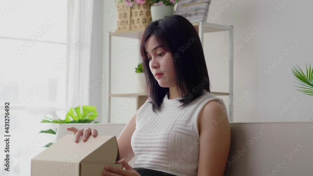 Slow motion Asian woman exciting open delivery box and surprise birthday gift. Female unbox with wow feeling and keep safe health at home in quarantine coronavirus with new normal social distancing. Slow motion Asian woman exciting open delivery box and surprise birthday gift. Female unbox with wow feeling and keep safe health at home in quarantine coronavirus with new normal social distancing.