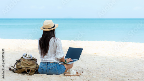 Lifestyle freelance woman using laptop working and relax on the beach.  Asia people success and together your work pastime and meeting conference on internet in holiday. Business and Summer Concept