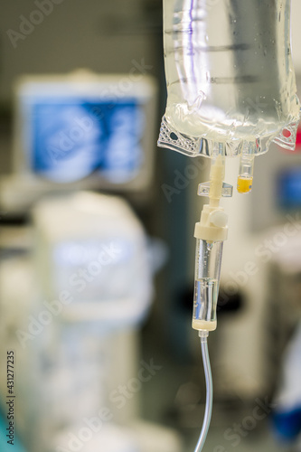 Intravenous fluid observation chamber - close up view in an operating theatre - background of surgical and xray monitors. 