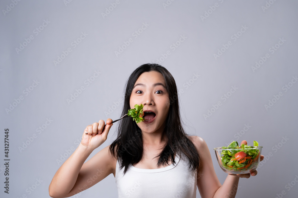 Asian woman eating salad isolated over white background. Asian woman eating salad isolated over white background.