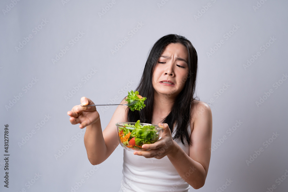 Asian woman trying to eat salad for diet isolated over white background. Asian woman trying to eat salad for diet isolated over white background.