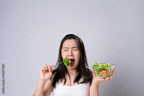 Asian woman trying to eat salad for diet isolated over white background.