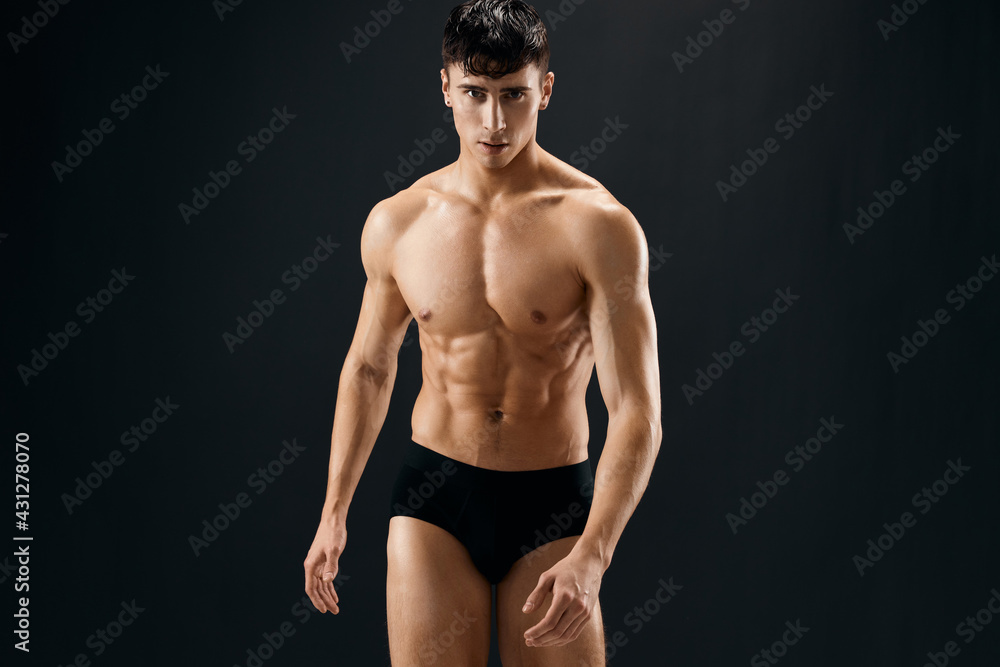 a man in dark shorts with a muscular body on a dark background bodybuilder a man in dark shorts with a muscular body on a dark background bodybuilder