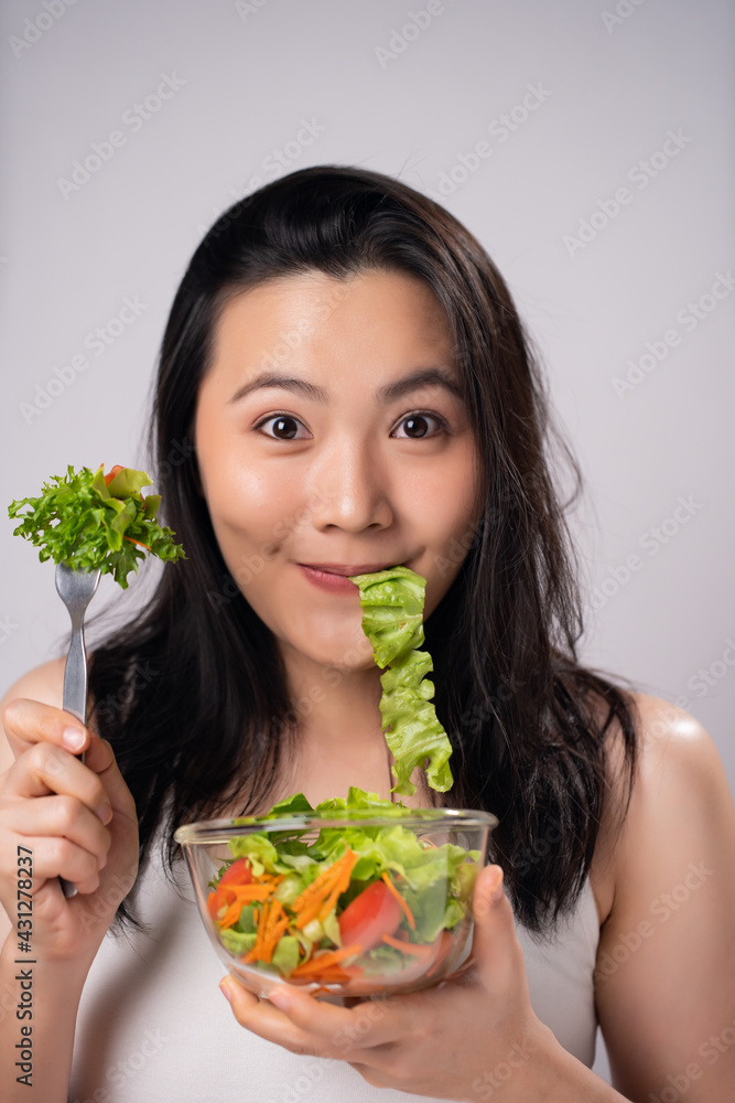 Asian woman eating salad isolated over white background. Asian woman eating salad isolated over white background.