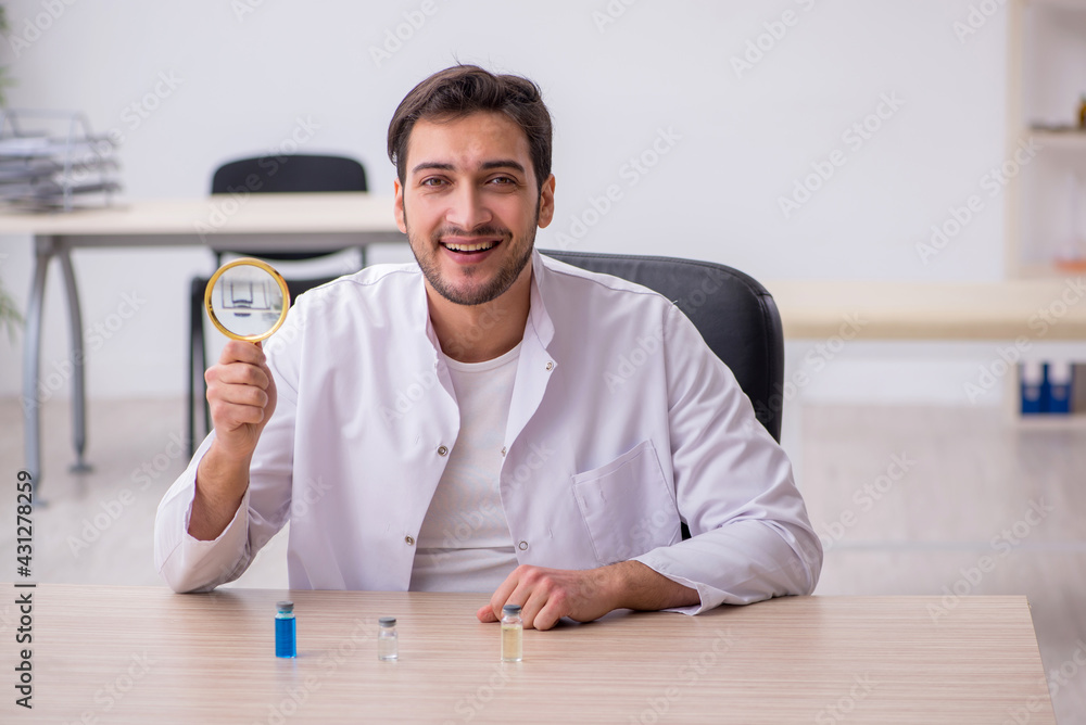 Young male chemist doctor holding vial