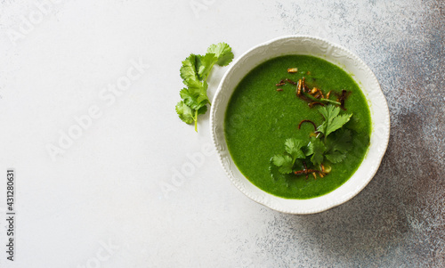 Bowl of broccoli, spinach, cilantro vegan soup on gray stone background. Flat lay. Copy space