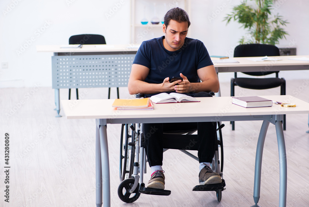 Young male student in wheel-chair preparing for exams