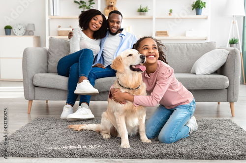 Young black girl hugging dog posing at home