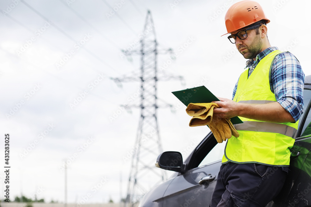 A man in a helmet and uniform, an electrician in the field. Professional electrician engineer inspects power lines during work. A man in a helmet and uniform, an electrician in the field. Professional electrician engineer inspects power lines during work.