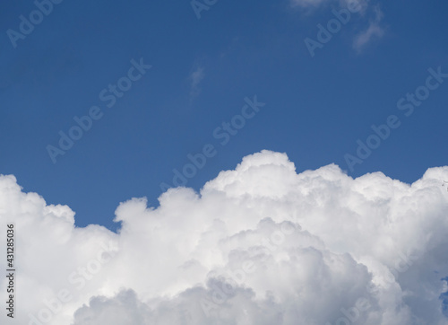 A huge white cloud with shadows in a clear dark blue sky. An airy natural background. Free space for text.