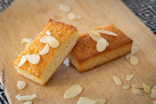 Gros plan sur des gâteaux financiers bien dorés sur une planche à découper parsemé d’amandes effilées