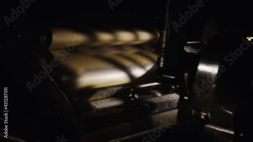 Old machinery working in a hazy, vintage workshop. Gears spinning, metal machines, historical printing studio. Industrial scene, antique, classic letterpress studio, making books, precision and art.